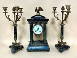 three candles and a clock sitting on a table