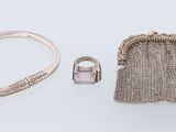 deux bagues en argent et une pochette en argent posées sur une surface blanche