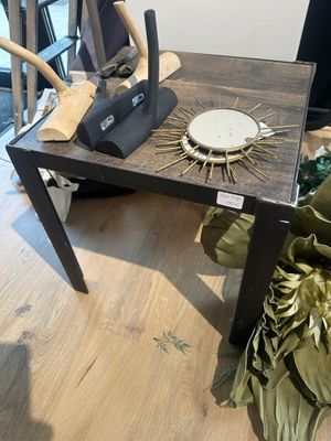 une petite table sur laquelle se trouve une horloge, dans une pièce
