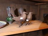 trois oiseaux posés sur une étagère à côté d'une assiette