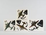 Plusieurs petits avions sont posés les uns sur les autres sur une surface blanche.