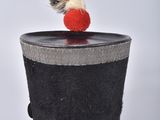 a black hat with a red pom pom sitting on top of it