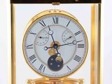 a gold clock with a blue moon in the center