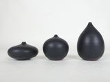 three black vases sitting next to each other on a white surface