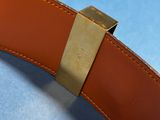 a brown belt with a gold buckle on a blue surface