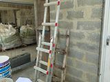 a ladder leaning up against a building next to buckets of paint