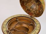 an antique brass plate on a stand with a cup on top of it
