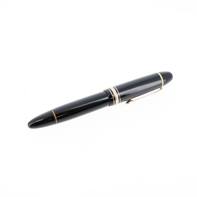 le stylo est noir avec des finitions dorées et repose sur une surface blanche