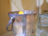 un seau en argent posé sur une table, contenant une orange