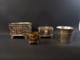 three silver cups and a silver cup on a black surface