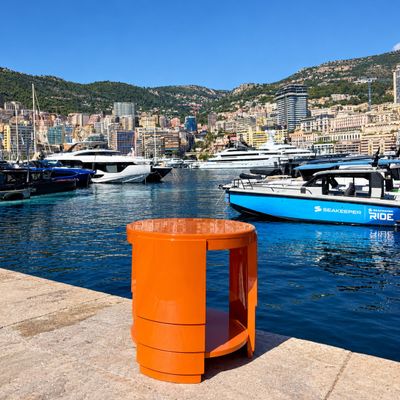 de nombreux bateaux à l'eau près d'un quai où se trouve une poubelle orange