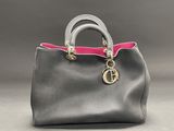 a grey and pink handbag with a gold charm on the handle