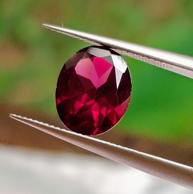 a close up of a red diamond being held by a pair of pliers