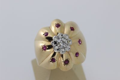 une image représentant une bague en or avec un diamant au centre, entouré de rubis
