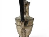 an old silver vase with a black handle on a stand