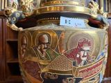 a gold vase with a painting on the wall behind it