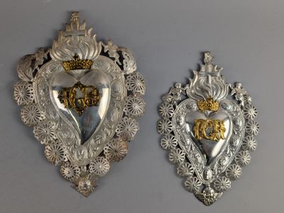 deux plaques en forme de cœur, en argent et en or, accrochées au mur