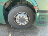 a green bus with a flat tire parked on the side of the road