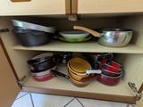 many pots and pans on a shelf in the kitchen