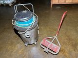 a bucket and a broom on the floor in a garage