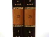 two brown books sitting on top of each other on a white surface