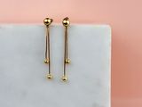 une paire de boucles d'oreilles en or posée sur un bloc de marbre