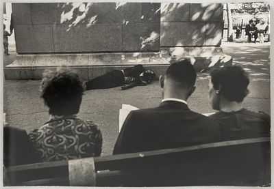trois personnes assises sur un banc qui regardent un homme allongé par terre