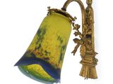yellow and blue glass wall light with a gold bell on a white wall