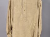 a tan shirt with black and red trims on a mannequin stand