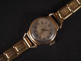 an image of a gold wrist watch on a black background