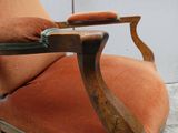 fauteuil de salon rembourré de couleur orange, avec structure en bois et accoudoirs