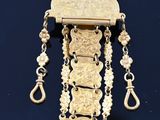 une image représentant un collier en or dont la chaîne pend sur le côté