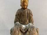 statue of a woman sitting on a rock with her hands in her lap