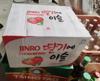 une boîte de fraises posée sur une boîte de sodas