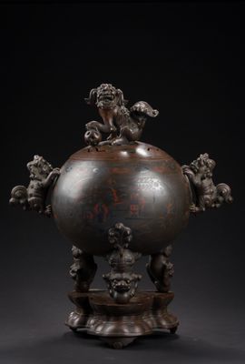 un grand vase en bronze orné de figures sur le dessus, posé sur un socle