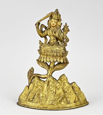 une statue en or représentant une femme assise sur un rocher