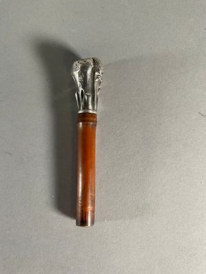 une petite brosse en argent et en bois posée sur une surface blanche