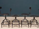three metal stools sitting next to each other on top of a cement floor