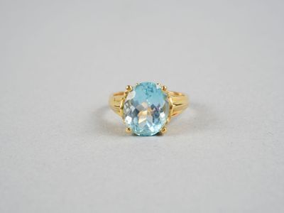 un gros plan d'une bague sertie d'une topaze bleue sur une surface blanche