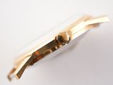 a close up of a gold watch on a white surface