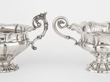 deux vases en argent munis d'anses et de poignées, sur fond blanc