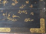 a black and gold painted box with flowers on it