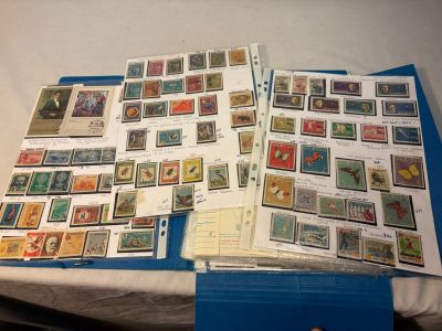 de nombreux timbres posés sur une table, à côté d'un classeur bleu