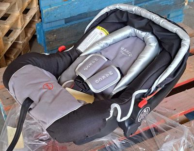 un siège auto pour bébé dans un sac en plastique posé sur une palette