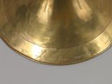a gold plate with a bell on it on a white table