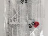 a small piece of paper with a red button on it