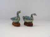 pair of ceramic ducks on wooden stand on white background