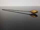 feuille d'or sur une surface noire, avec un reflet à la surface