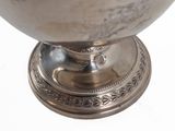a silver bowl on a stand on a white surface