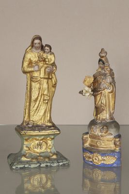 trois figurines représentant Jésus et Marie posées sur une table en verre